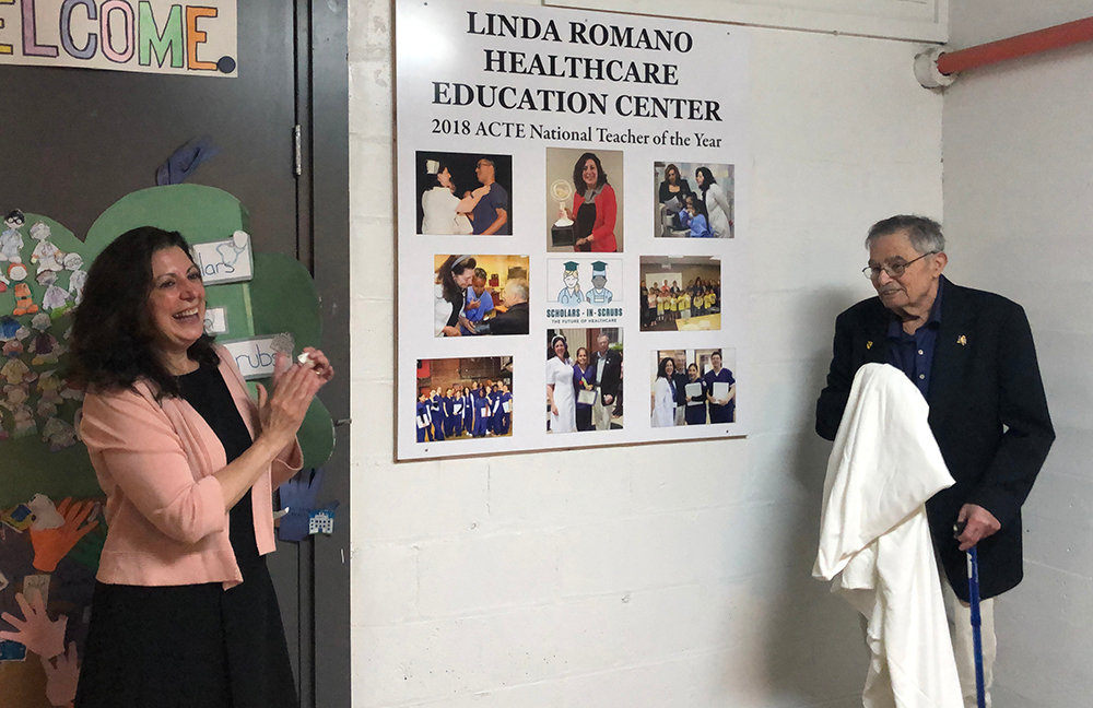 Linda Romano applauds as she and William Kaplan unveil the new sign for the Linda Romano Healthcare Education Center at the Newburgh Armory Unity Center.