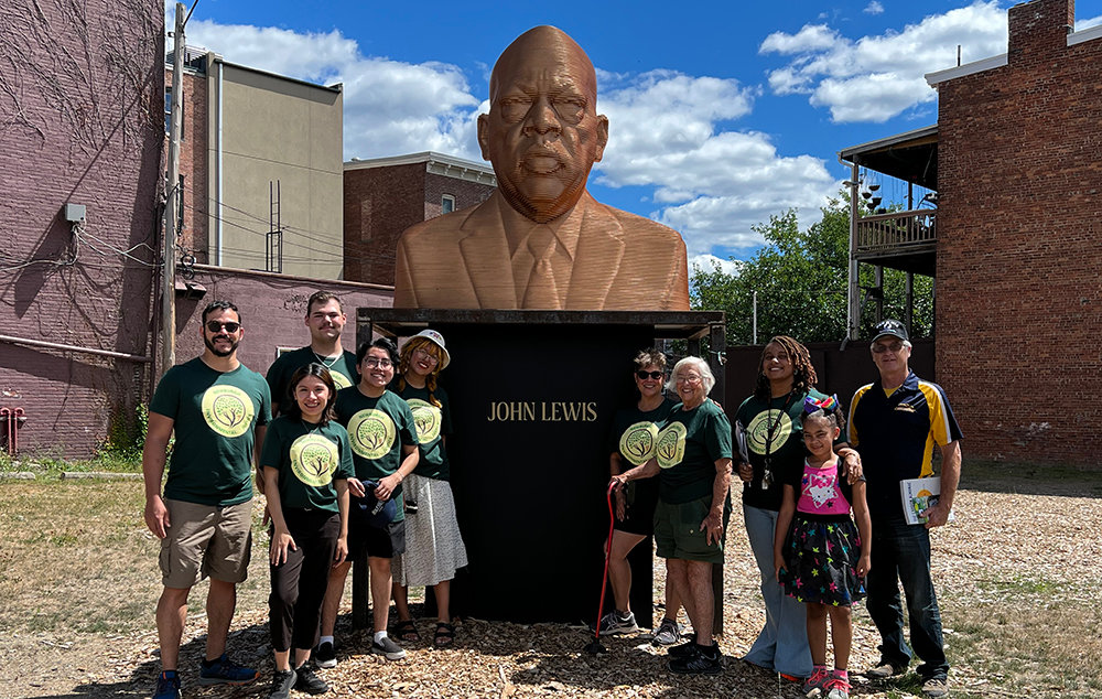 The Environmental Justice Fellows and supporters gather in front of the image of John Lewis located on the corner of Liberty St. and Broadway.