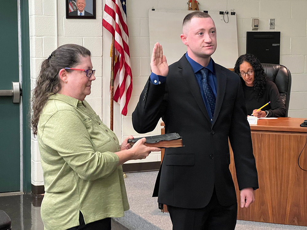 [L-R] Brandon Abrams recites the oath of office for the town police department as Beth Schwartz Abrams holds the bible for him.