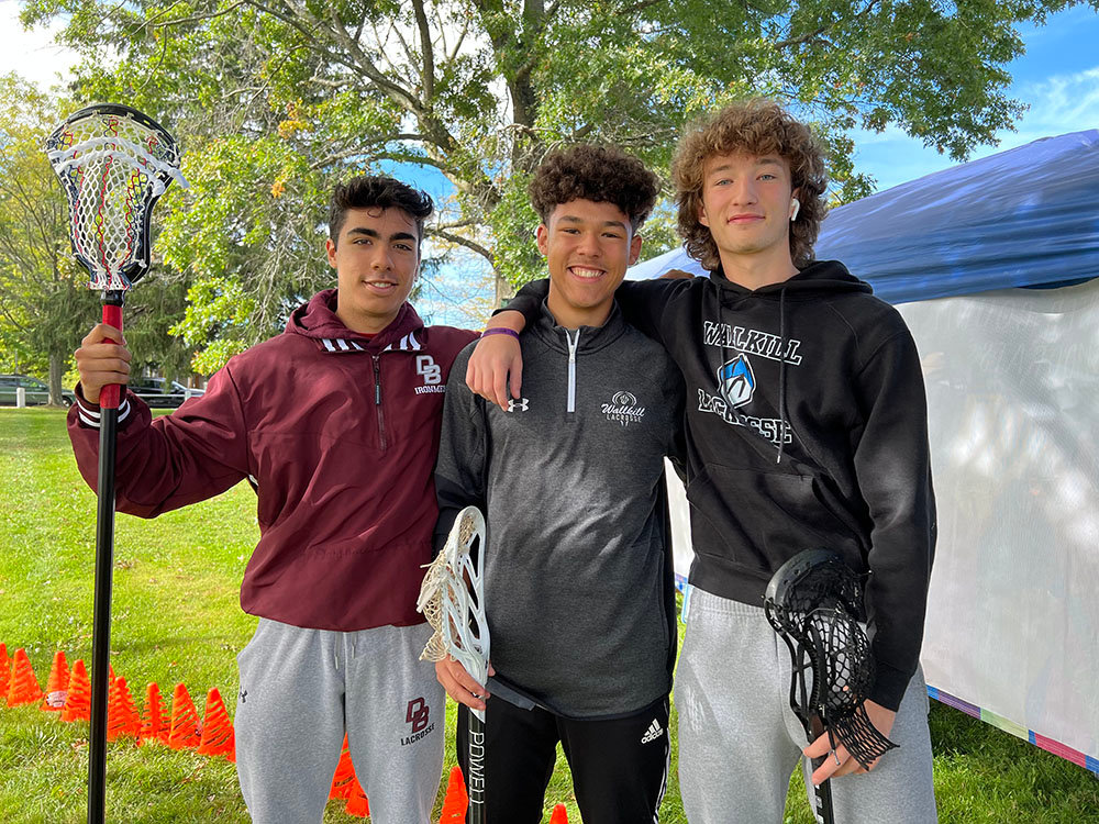 [L-R] Ian Rodriguez, Alex DeCastro and Brent Decoeur volunteer with lessons at the Wallkill Youth Lacrosse booth.