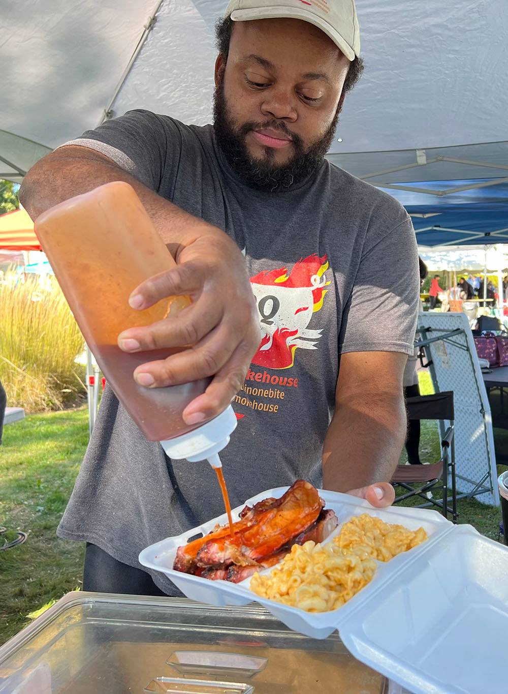 Marlon Moore, co-owner of LaVelle’s Smokehouse, adds a little extra sauce to some prepared ribs along with a side of macaroni and cheese.