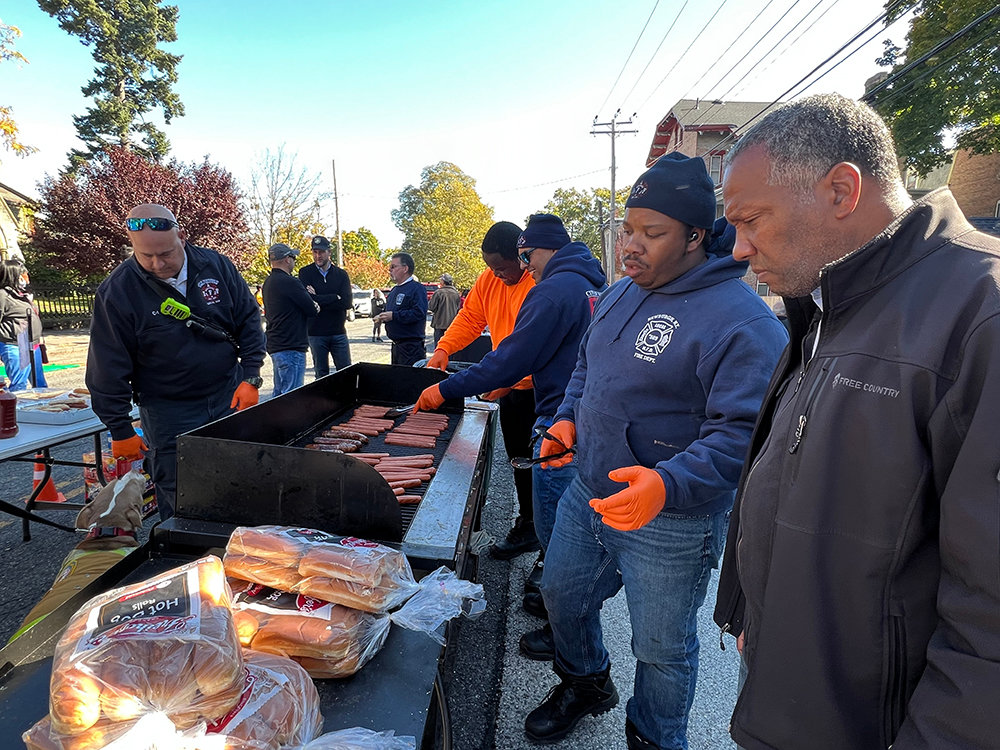 Councilman Anthony Grice [far right] speaks with several members of the City of Newburgh Firefighters Union IAFF Local 589 while they prepare home cooked hot dogs.
