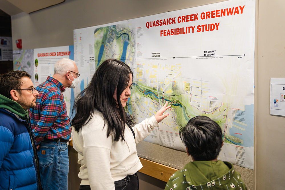 Marichen Montiel [center] speaks with a young attendee about the feasibility study for the creek project.