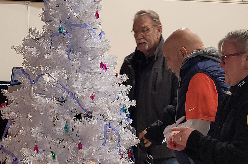 Cal Masten, Ed Molinelli, and Christina Johosky hang bulb-shaped ornaments on Marlborough’s tree commemorating fallen police officers. In all 107 bulbs went up - one for each U S. officer killed in the line of duty in the last year.